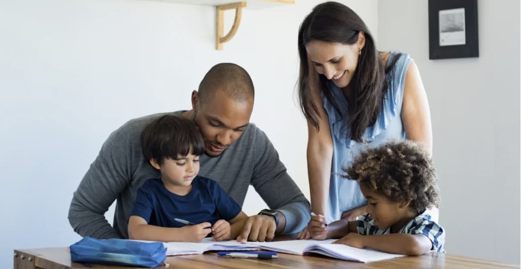 Two parents working with their children on schoolwork at home